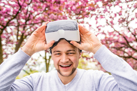 Young man wearing virtual reality goggles outside in spring natureの写真素材
