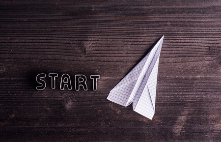 Office desk with start up sign made of cookie cutters and paper airplane. Flat lay. Workplace. Studio shot on wooden background. Copy spaceの写真素材