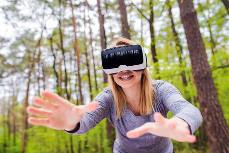 Blond woman wearing virtual reality goggles outside in spring natureの写真素材