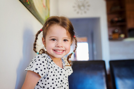 Cute little girl with two braids in dotted t-shirt smilingの写真素材