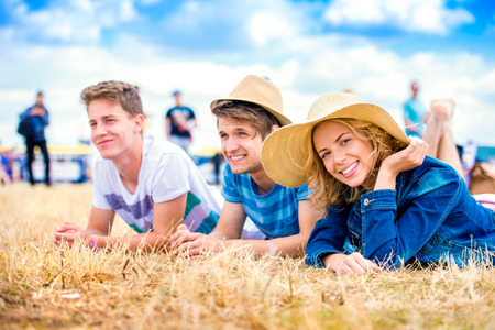 Group of teenage boys and girl at summer music festival, lying on the ground