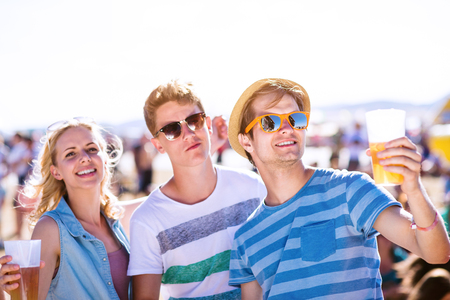 Group of teenage boys and girls with beers in a crowd at summer music festival, , sunny dayの写真素材