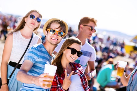 Group of teenage boys and girls with beers in a crowd at summer music festival, , sunny dayの写真素材