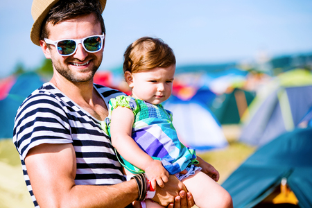 Young father with his baby daughter between tents at summer music festivalの写真素材