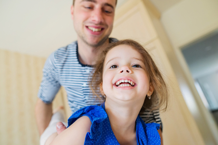 Young father having fun with his cute little daughter, holding her, carrying herの写真素材