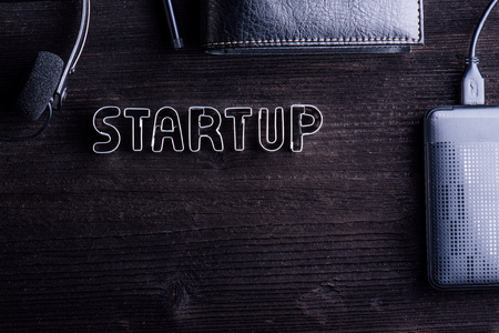 Start up composition. Headset, external hard drive and various things around desk and sign made of...