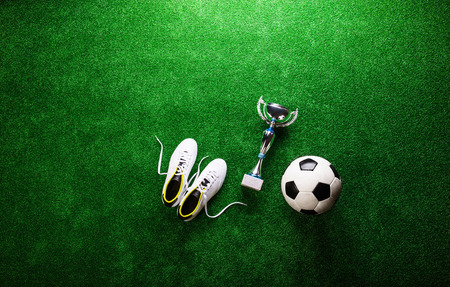 Soccer ball, cleats and trophy against artificial turf, studio shot on green background. Copy space.の写真素材