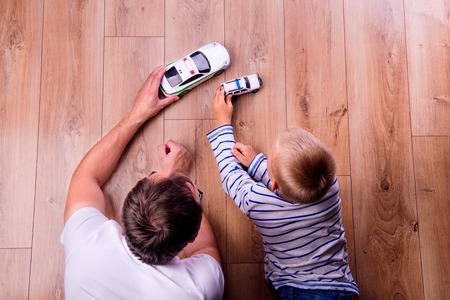 Unrecognizable father with his son playing with cars. Studio shot on wooden background.の写真素材