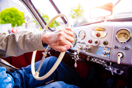 Close up unrecognizable man driving a veteran car, hands on steering wheelの写真素材