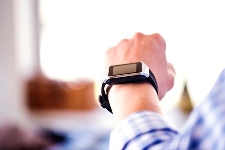 Close up of unrecognizable man in blue checked shirt using smart watch