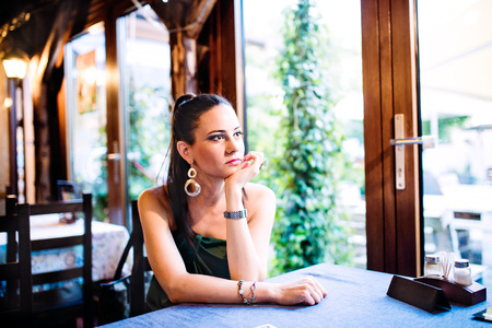 Young beautiful woman sitting at the table in bar or clubの写真素材