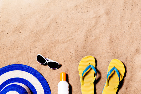 Summer vacation composition with a pair of yellow flip flop sandals, hat, sunglasses and suntan...