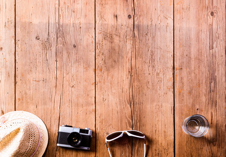 Summer vacation composition. Hat, vintage camera, sunglasses and glass of water on wooden...