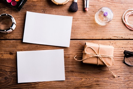 Empty paper notes, little package and various make up products. Studio shot on wooden background. Copy space, flat lay.の写真素材