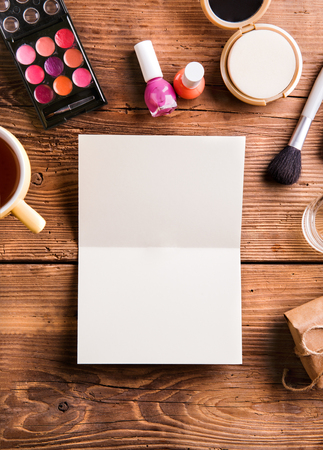 Empty greeting card laid on table. Various make up products. Studio shot on wooden background. Flat lay, copy space.の写真素材