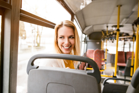 Beautiful young woman traveling by bus, having fun in town.の写真素材