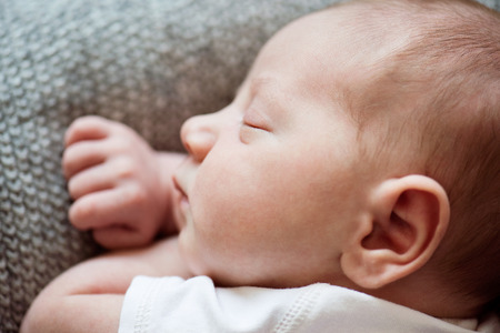 Cute little newborn baby boy lying on bed, sleeping, close up