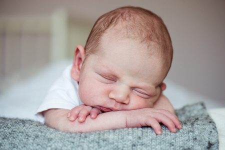 Cute little newborn baby boy lying on bed, sleeping, close upの写真素材