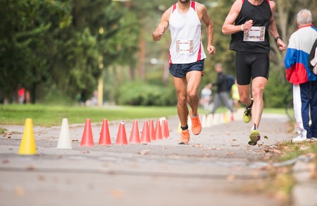 Group of unrecognizable runners sprinting outdoors. Sportive people training in a urban area,...