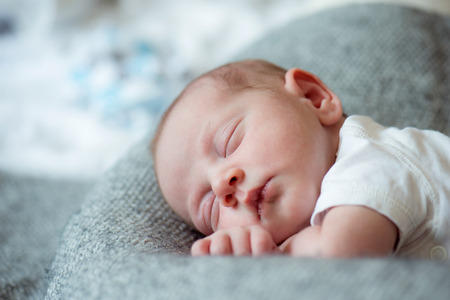 Cute little newborn baby boy lying on bed, sleeping, close upの写真素材