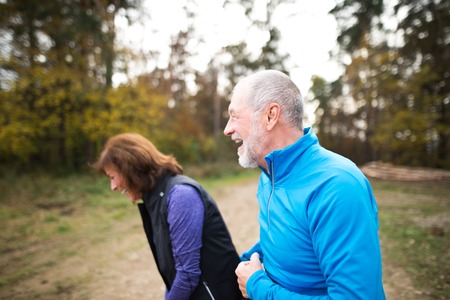 Beautiful active senior runners outside in sunny autumn forestの写真素材