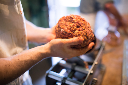 Unrecognizable man making sausages the traditional way at home. Holding meat ball in his hands, close up.の写真素材