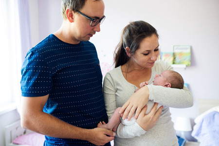 Young father and mother holding their newborn baby son in the arms