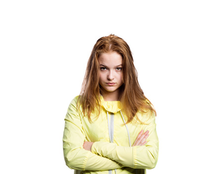 Teenage girl in neon yellow running jacket, holding head. Beautiful sportswoman. Studio shot on white background, isolated.の写真素材