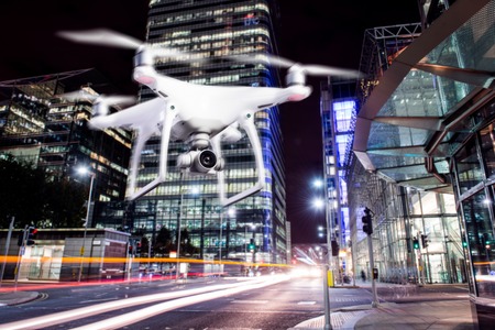 Close up of hovering drone taking pictures of city of London at night