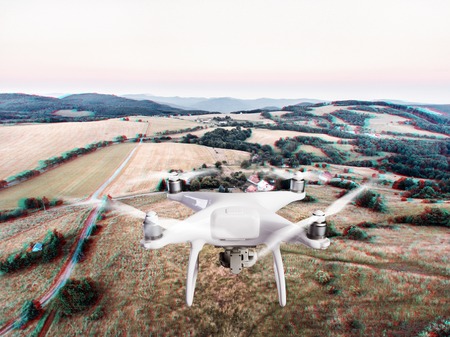 Hovering drone taking pictures of green grasslands, houses and forest. Slovakia, Nova Bana. Aerial view.の写真素材