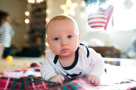 Cute little baby boy under Christmas tree lying on checked blanket.の写真素材