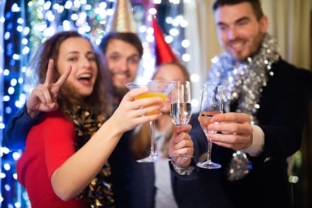 Group of friends celebrating the end of the year, having party on New Years Eve, clinking with champagne.の写真素材
