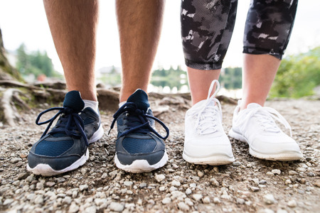 Legs of unrecognizable running couple in sports shoes on rocky path. Close up.の写真素材