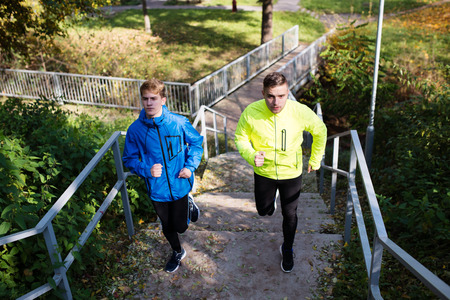 Two athletes running on stairs in sunny autumn nature.の写真素材