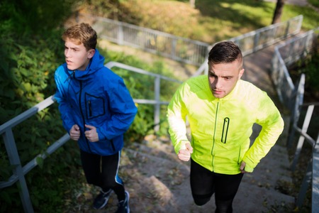 Two athletes running on stairs in sunny autumn nature.の写真素材