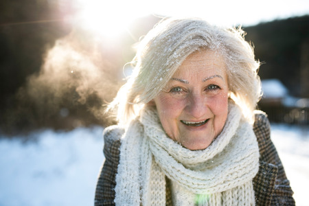 Beautiful senior woman on a walk, covered by snowの写真素材