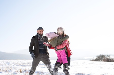 Father and mother with their daughter, playing in the snow.の写真素材