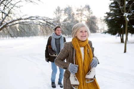 Senior couple in sunny winter nature going ice skating.の写真素材