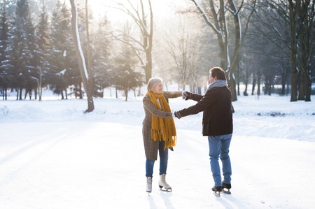 Senior couple in sunny winter nature ice skating.の写真素材