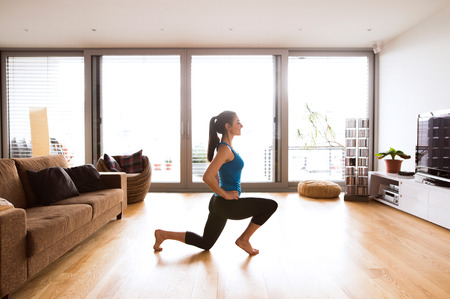 Young woman exercising at home, stretching legs.の写真素材
