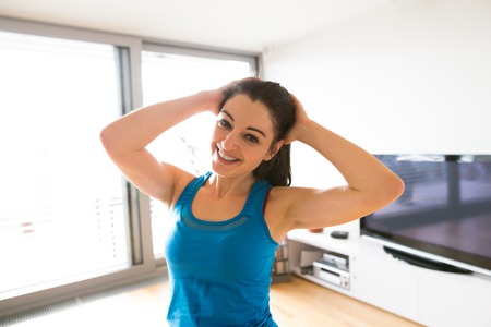 Young woman exercising at home, stretching neck.の写真素材
