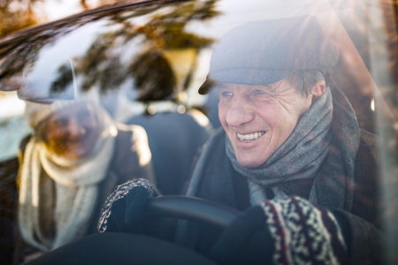 Senior couple in winter clothes driving a carの写真素材