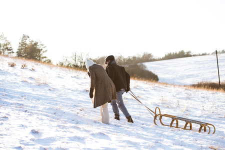 Beautiful senior couple on a walk pulling sledge, winter day.の写真素材