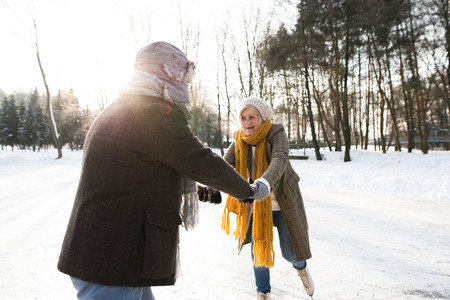 Senior couple in sunny winter nature ice skating.の写真素材