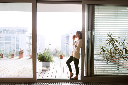 Woman relaxing on balcony holding cup of coffee or tea