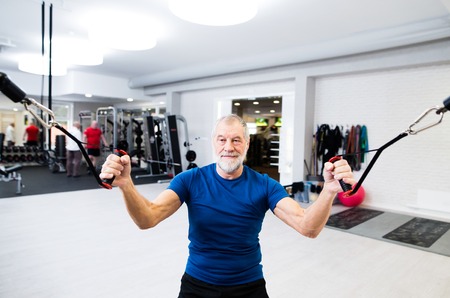 Fit senior man in gym working out with weights.