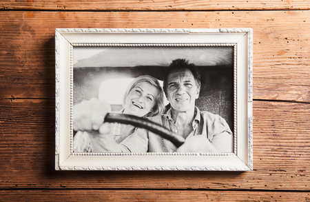 Photo of seniors in picture frame laid on wooden background.の写真素材
