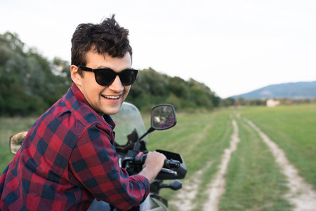 Young man enjoying a motorbike ride in countryside.