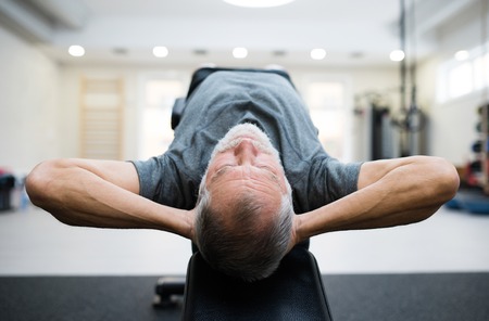 Fit senior man in gym working his abs, doing crunches.の写真素材