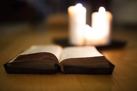 Bible laid on wooden floor, burning candles in the backgroundの写真素材
